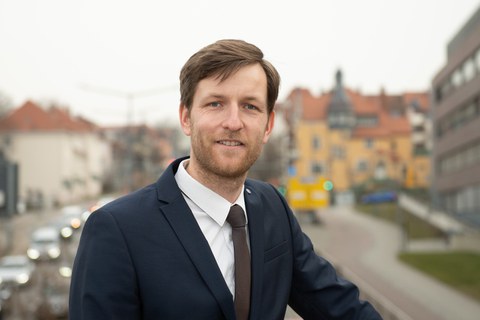 Pascal Kerschke im halbporträt draußen. Im Hintergrund eine Stadt.