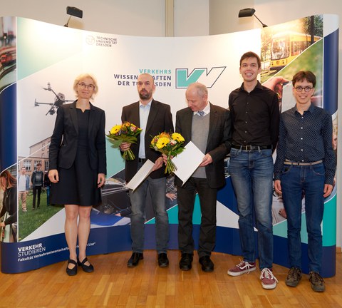 Menschen stehen vor einer Bildwand, links eine Frau und dann 5 Männer