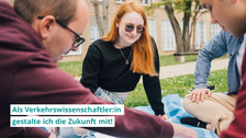 Eine Studentin und zwei Studenten sitzen auf einer Decke auf einer Wiese im Kreis und schauen auf eine Papierskizze in der Mitte. Ein Bildtext schreibt: "Als Verkehrswissenschaftler:in gestalte ich die Zukunft mit!"