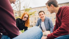 Studierende sitzen auf einer Wiese im Kreis.