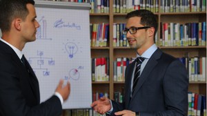 Two researchers are talking to each other in front of a flipchar