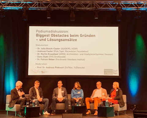 Panel discussion – six participants seated in a semicircle on a sofa