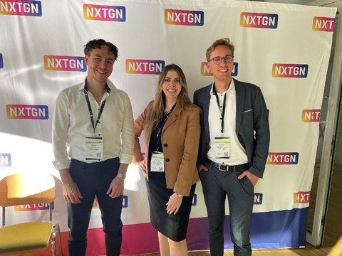 Three people posing in front of a photo wall