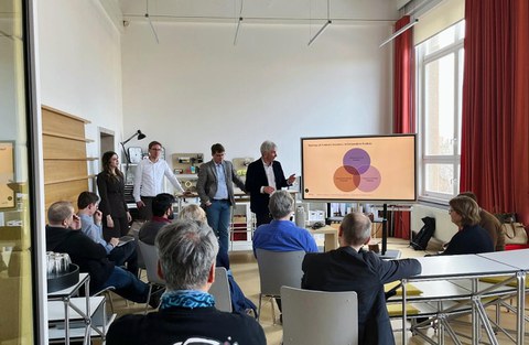 Teilnehmende des Forschungskolloquiums schauen gespannt auf Vortragenden