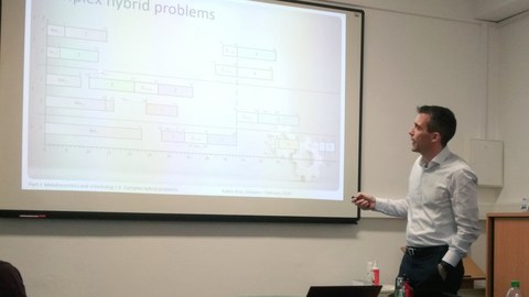 Ein Mann (Ruben Ruiz Garcia) hält einen Vortrag und zeigt mit einem Pointer auf die Präsentation.