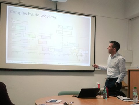 A man (Ruben Ruiz Garcia) gives a lecture and points to the presentation with a pointer.
