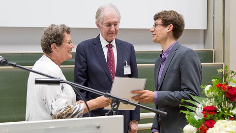 Das Bild zeigt 2 Männer und eine Frau bei einer Urkundenübergabe.