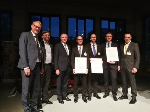 Group picture: Prize winners with certificates and persons in charge wear suits.
