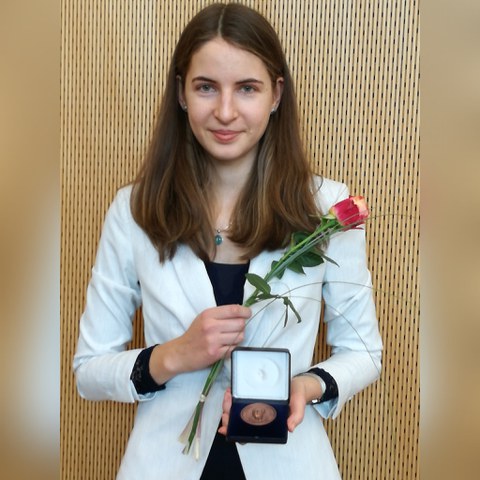 A woman (Maria Beranek) with a medal in a box and a rose in her hand.