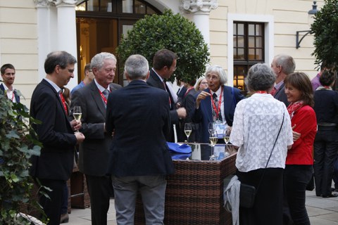 Several people are standing at tables outside and talking to each other.