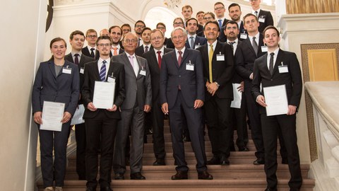 Gruppenbild auf einer Treppe. Manche Personen halten Urkunden in der Hand.