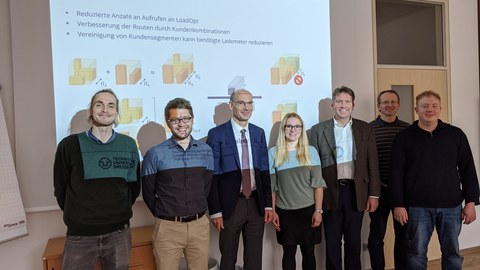 Projektteam: sieben Personen vor einem Beamer-Bildschirm.