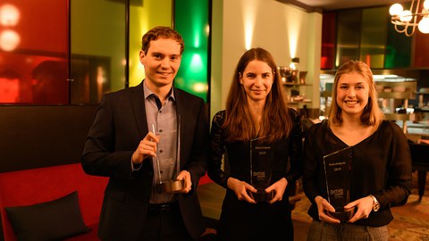 1 Mann und 2 Frauen mit Glaspokalen in den Händen.