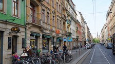 Es ist eine Straße in der Dresdner Neustadt zu sehen. Man sieht Straßenbahnschienen, Läden und viele Fahrräder  