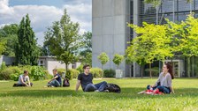 Zu sehen sind vier Studierende, die auf der Wiese vor dem Hörsaalzentrum sitzen 