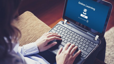 Es ist eine Frau zu sehen, die an einem Laptop sitzt