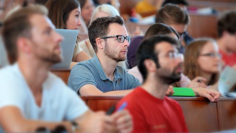 Es sind Studierende zu sehen, die in einem Hörsaal in einer Vorlesung sitzen