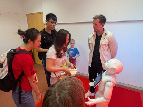 Zu sehen ist die Interaktion von Besuchern mit einem humanoiden Roboter 