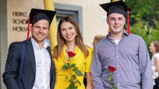 Es sind drei Absolventen zu sehen