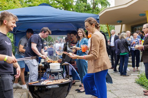 Es ist ein Grillstand auf einem Sommerfest zu sehen