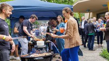 Es ist ein Grillstand auf einem Sommerfest zu sehen