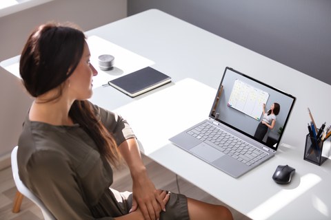 Eine junge Frau schaut eine Online-Lehrveranstaltung.