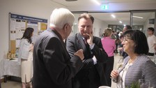 Es sind drei Gäste bei einer Festveranstaltung zu sehen, die sich unterhalten