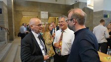 Zu sehen sind viele Menschen, die sich bei einer Feier im Foyer des Schumann-Baus unterhalten 