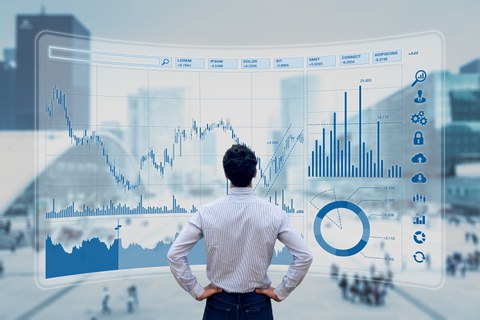 Es ist ein Manager zu sehen, der vor einem großen Dashboard mit vielen Zahlen und Grafiken steht