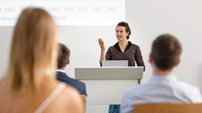 You see a woman holding a speech