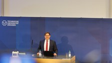 Man sieht Prof. Leßmann, der das Publikum begrüßt.