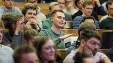 Ein Studierender stellt eine Frage an die Podiumsdiskussion.