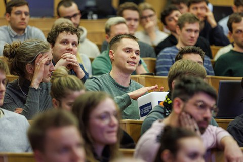 Ein Studierender stellt eine Frage an die Podiumsdiskussion.