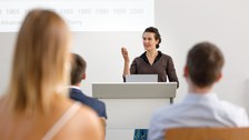 Es ist eine Doktorandin zu sehen, die einen Vortrag hält