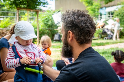  Ein Vater spielt mit seinem Kind auf einem Spielplatz des Kindergartens "Campus-Kiste". Das Kind hält Spielzeug in der Hand.