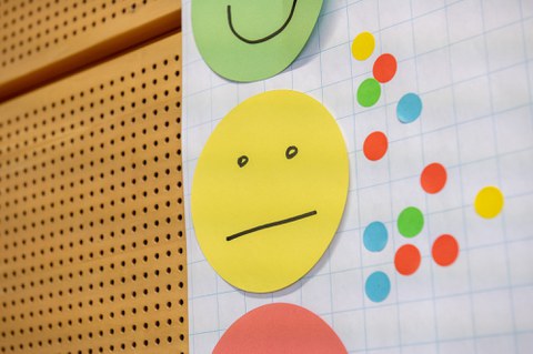 Foto zeigt ein Flipchart mit drei farbigen Smileys und kleinen bunten Kreisen darauf.