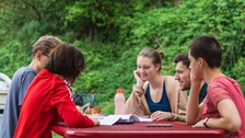 Foto von fünf Studenten, die am Imbisstisch am Hörsaalzentrum sitzen und zusammen lernen. 