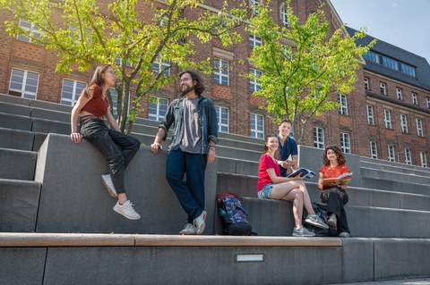 Bild zeigt 5 Studierende, die sich auf den Treppen am Fritz-Foerster-Bau unterhalten und zusammen lernen.