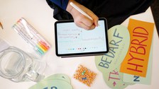 Foto einer Hand, die mit einem Stift auf einem Tablet Notizen aufschreibt.