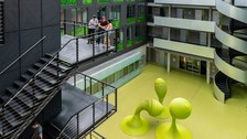 Foto: Studenten auf einer Treppe im Foyer des Andreas-Pfitzmann-Baues mit der Skulptur "Bubbles".