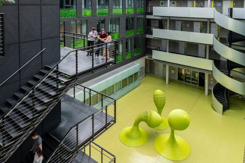 Foto: Studenten auf einer Treppe im Foyer des Andreas-Pfitzmann-Baues mit der Skulptur "Bubbles".
