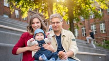 Foto eines studentischen Paares, das mit einem etwa 1-jährigem Kind auf dem Schoß auf den Fritz--Förster-Bau-Treppen sitzt.