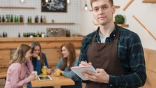 Man sieht einen Studierenden, der in einem Cafe arbeitet.