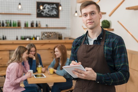 Man sieht einen Studierenden, der in einem Cafe arbeitet.