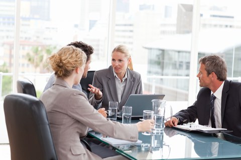 Das Foto zeigt mehrere Personen in Businesskleidung während eines Meetings in einem Büro.