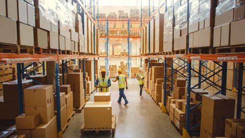 Einzelhandelslager mit Waren in Kartonboxen, Scannen und Sortieren von ArbeiterInnen, Lagerbestand mit Palettenstaplern und Gabelstaplern.