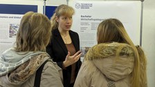 Man sieht eine Mitarbeiterin im Gespräch mit Studierenden.