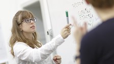 Studentin an Whiteboard mit Stift in der Hand