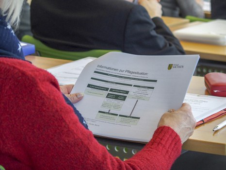 Teilnehmerin betrachtet Unterlagen zum Vortrag