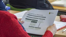 Teilnehmerin betrachtet Unterlagen zum Vortrag
